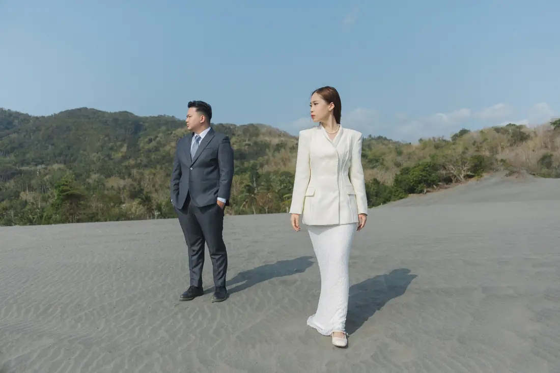 Irfan and Stephanie standing on sand with green hills behind